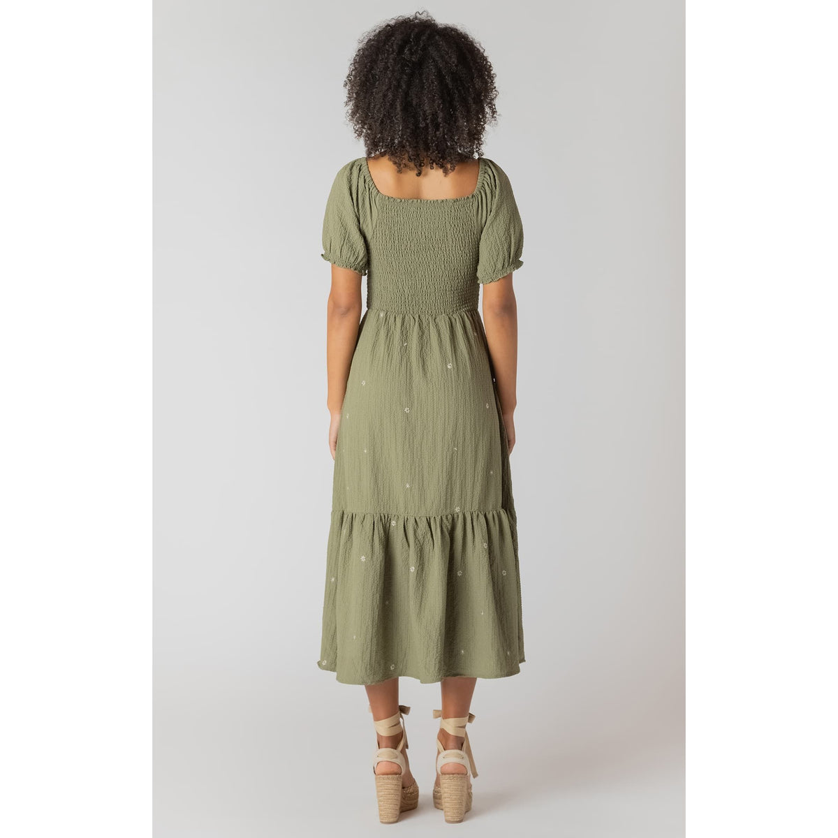 Room 34 olive green smocked tiered maxi dress with puff sleeves and embroidered flowers on model.