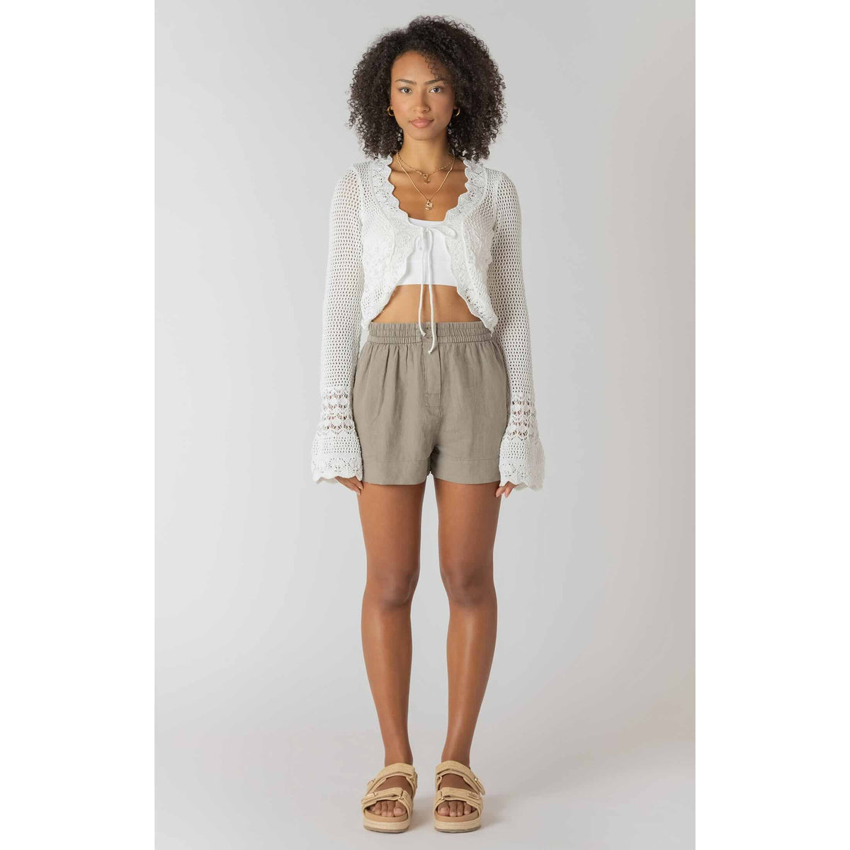 Room 34 Tie Front Crochet Cardigan worn by model over a white crop top and beige shorts.