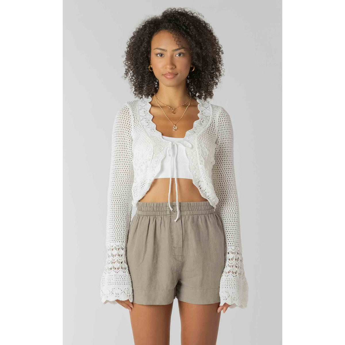 Room 34 Tie Front Crochet Cardigan with scalloped lace edges over white crop top and beige shorts.
