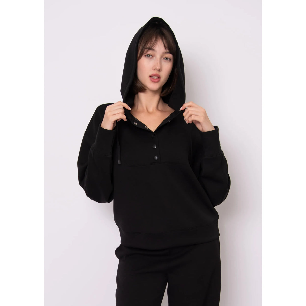 Model wearing Sallie Soft Knit Snap Front Hoodie in black with hood up and front snaps.