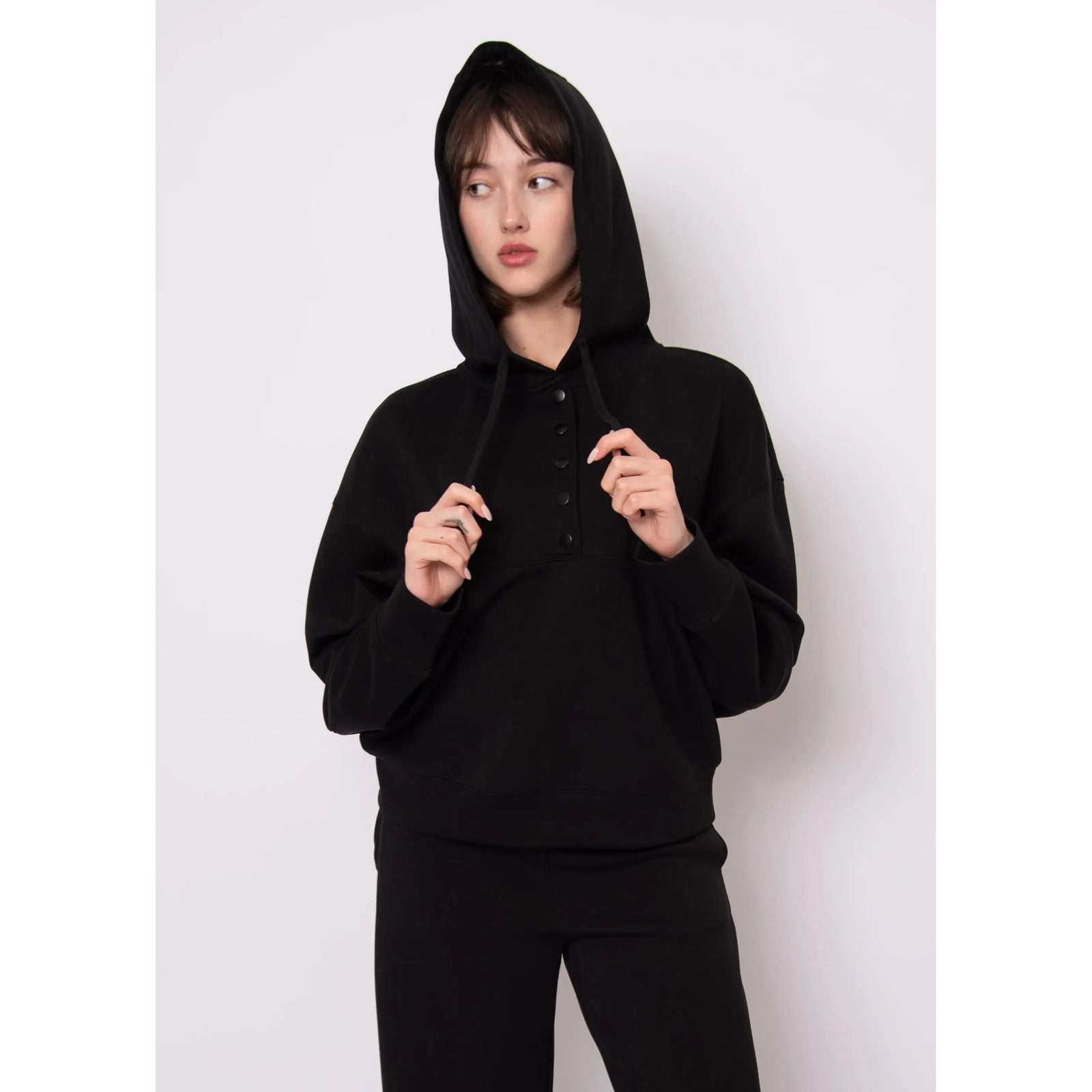 Model wearing Sallie Soft Knit Snap Front Hoodie in black with hood and snap-front closure.