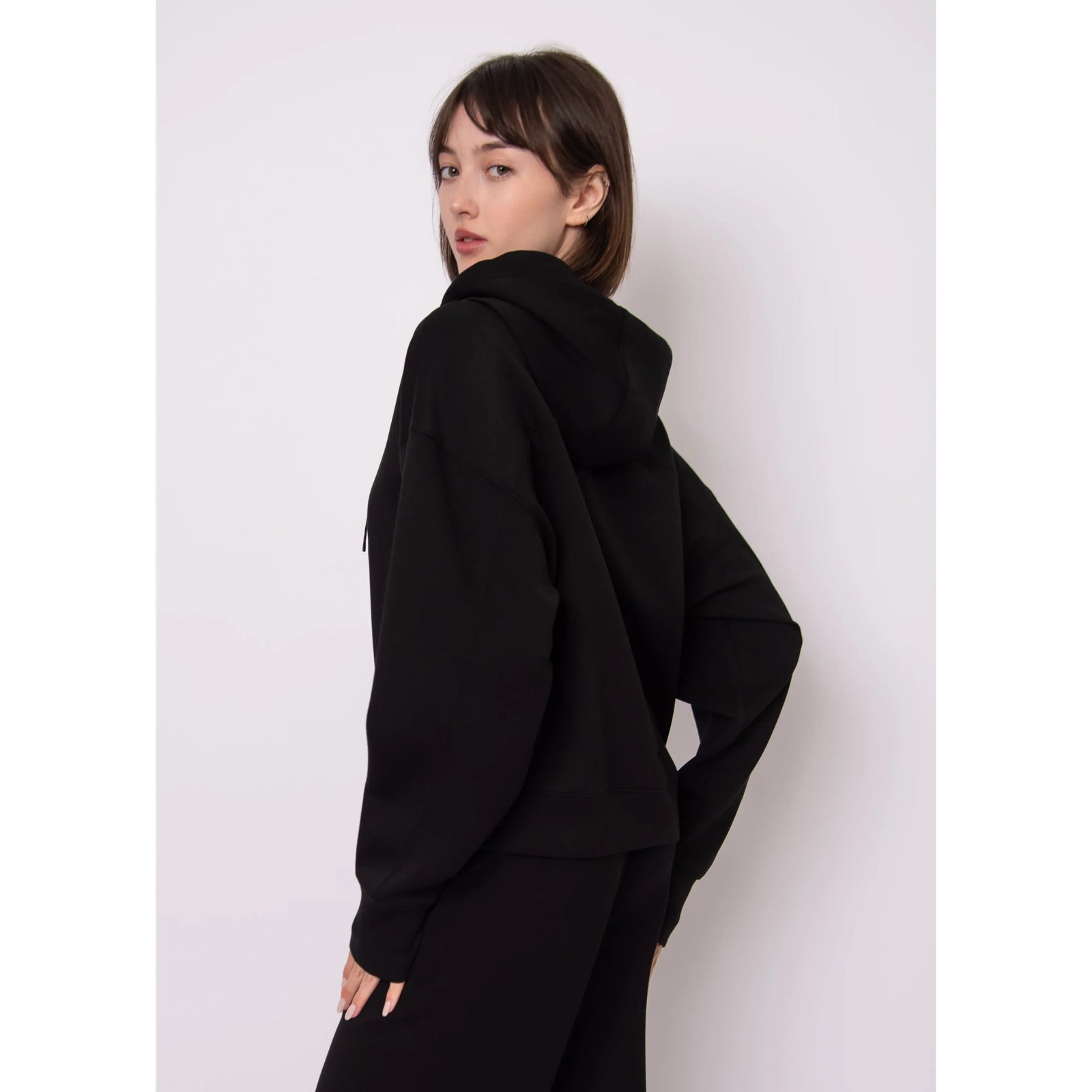 Model wearing Sallie Soft Knit Snap Front Hoodie in black; back/side view, cozy fall layering.