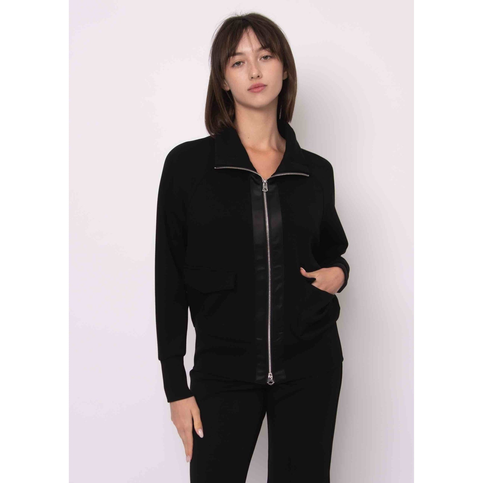 Saruna Soft Knit Mock Zip Up in black with satin trim, zip front, mock neck, worn by model.