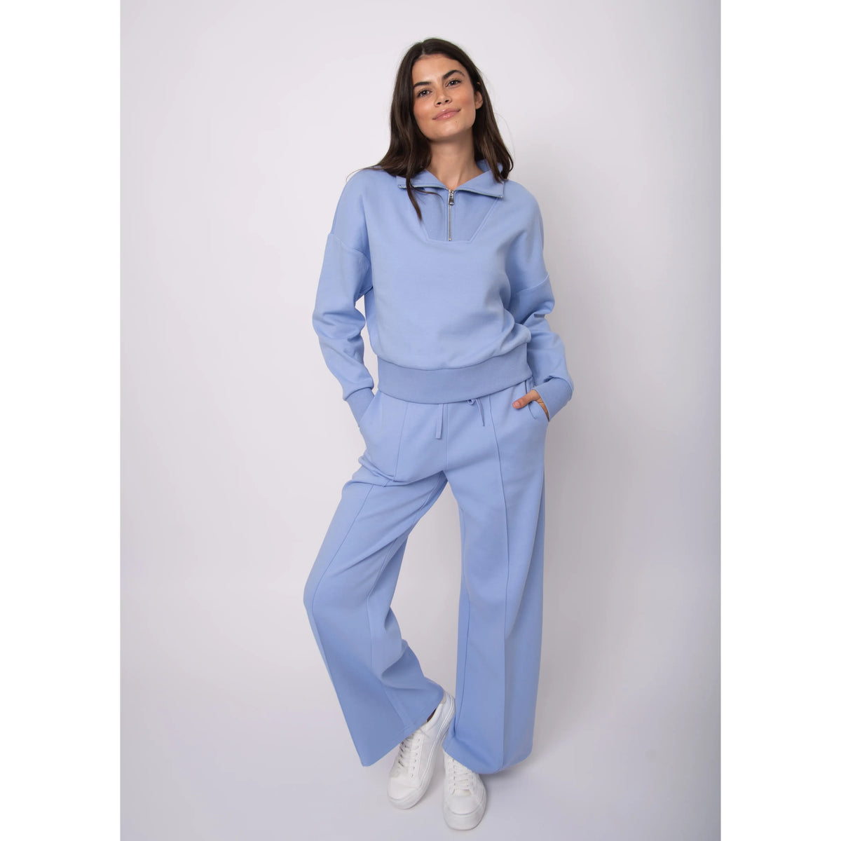 Model wearing Seanni Soft Knit Half Zip Pullover in light blue with matching joggers and white sneakers.