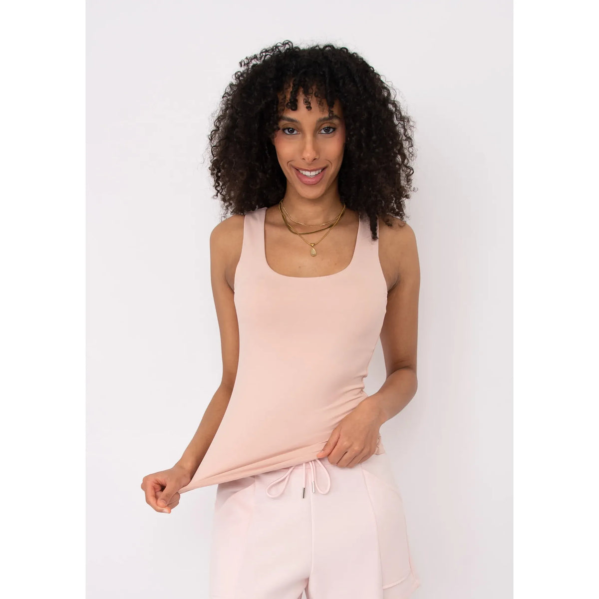 Model wearing Second Skin Tanith Double Uneck Tank Top in blush pink with layered necklaces.