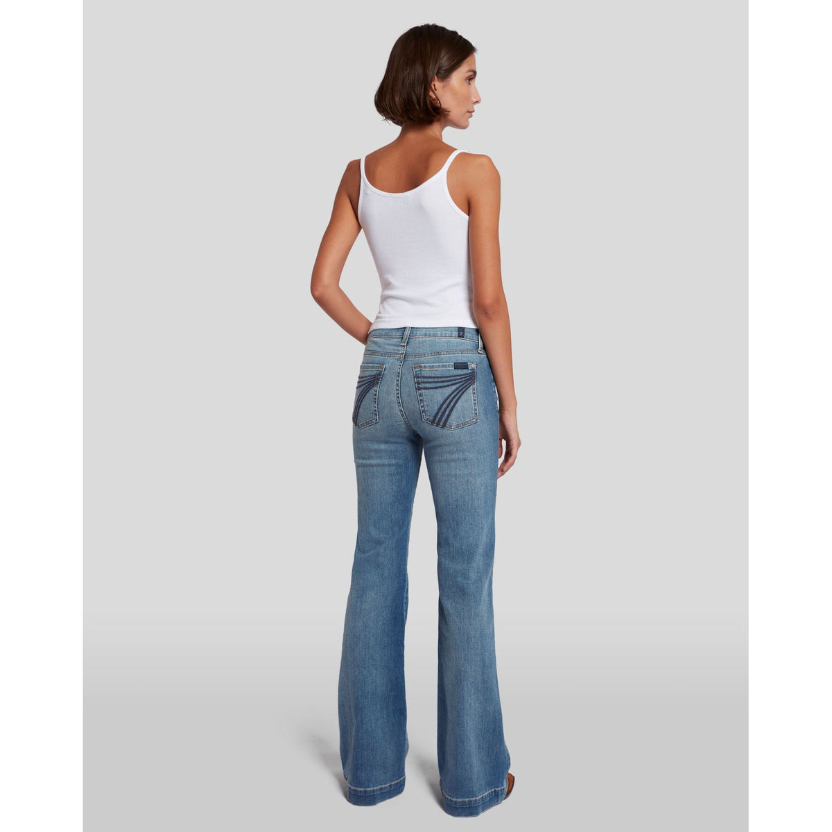 7 for all Mankind Dojo in Slim Illusion jeans, back view on model, mid-rise with subtle flare in light blue denim.