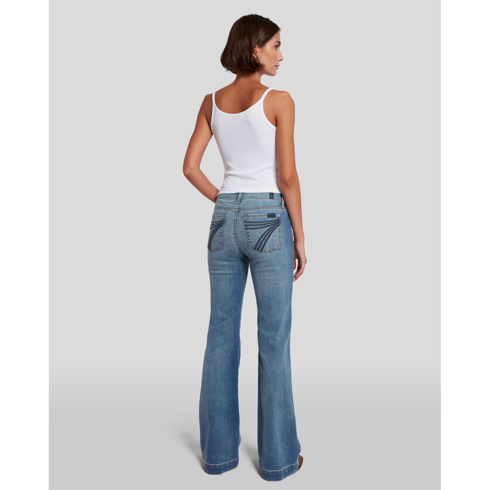 7 for all Mankind Dojo in Slim Illusion jeans, back view on model, mid-rise with subtle flare in light blue denim.