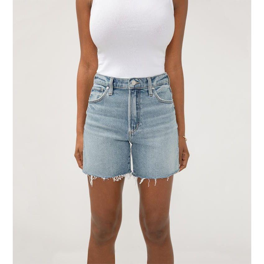 Stylish woman wearing Silver Highly Desirable Long Shorts in medium-light indigo, perfect for a trendy summer look.