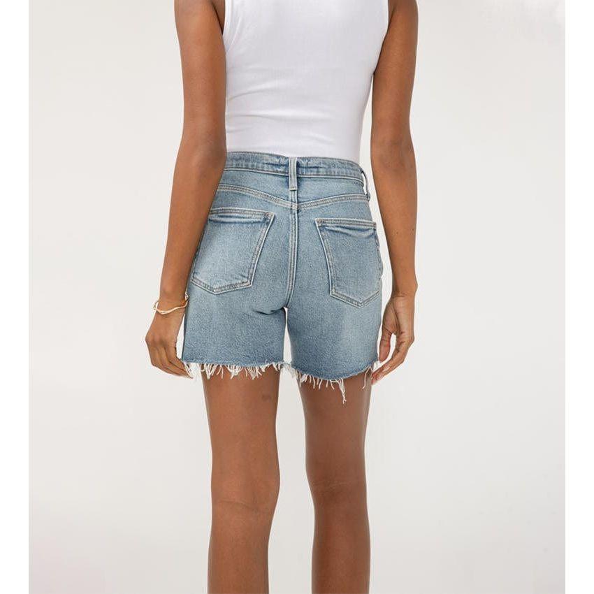 Stylish woman wearing Silver Highly Desirable Long Shorts in medium-light indigo, showcasing a flattering fit.