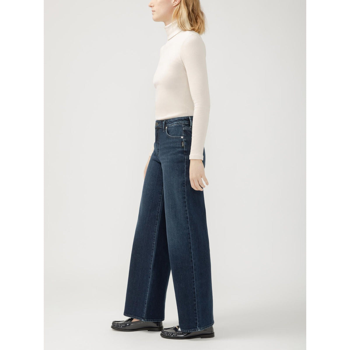 Side view of a woman wearing Silver Isbister Wide Leg Denim in Bijou with a white turtleneck.