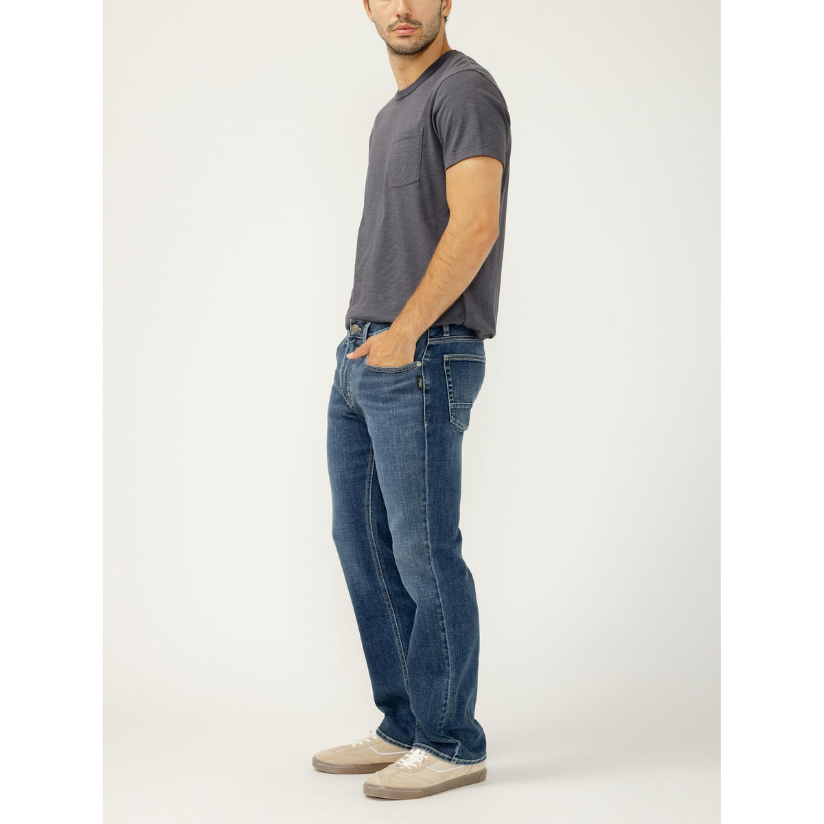 Model wearing Silver Jace Slim Bootcut jeans in Tate wash with gray tee and beige sneakers.