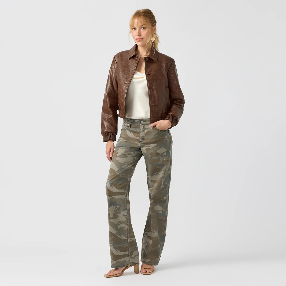 Low rise camo jeans with a fitted waist and loose straight leg, styled here with a brown cropped leather jacket and white top.
