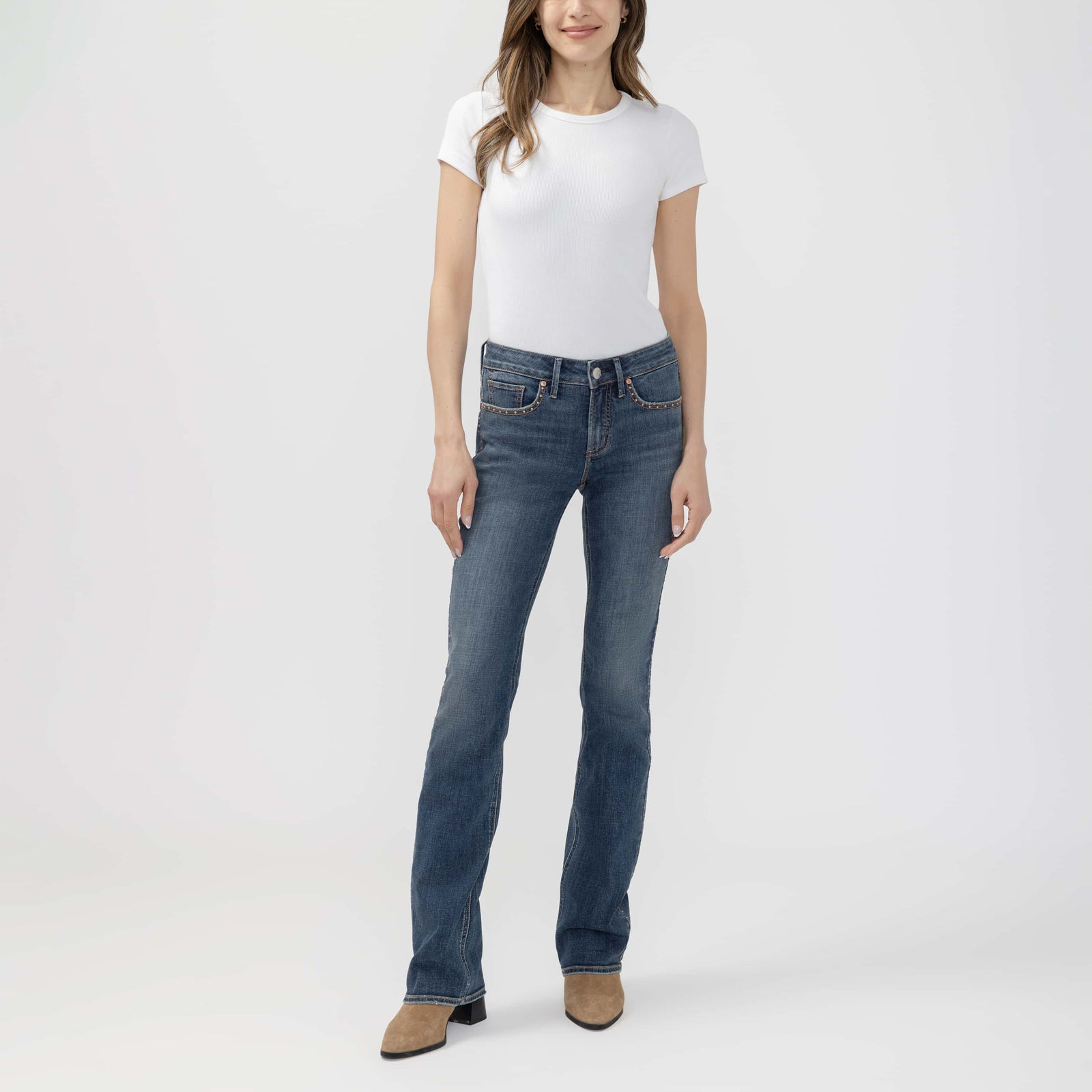 Model in a white tee and blue jeans showcases Suki Slim Boot in Seraphina, tan suede ankle boot.