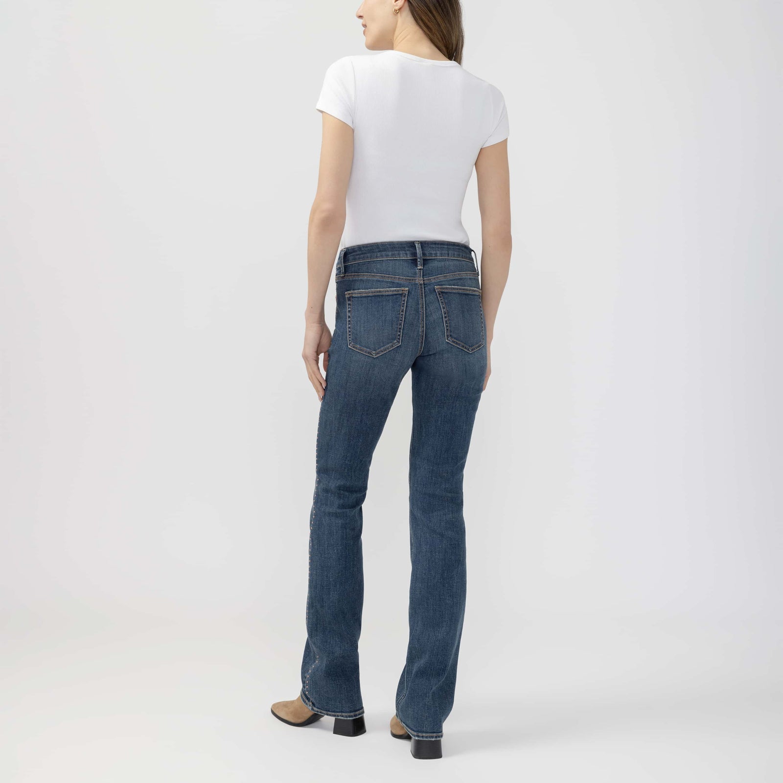 Back view of a woman in a white tee wearing Suki Slim Boot jeans in Seraphina wash.