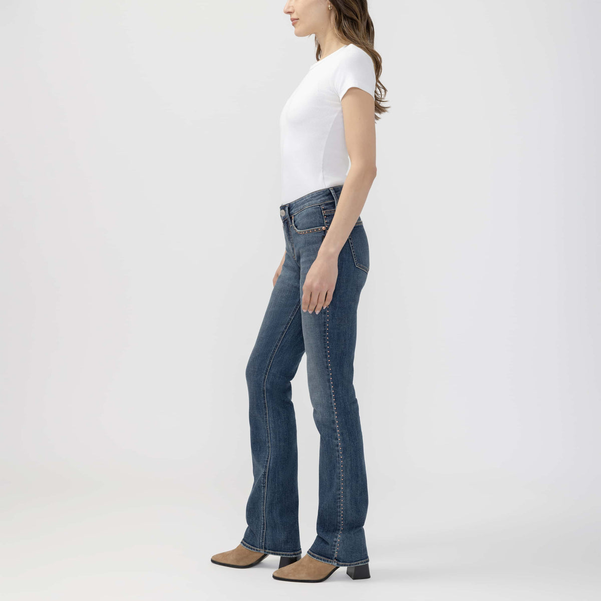 Side profile of a model wearing a white top and blue jeans, featuring tan suede Suki Slim Boot in Seraphina.