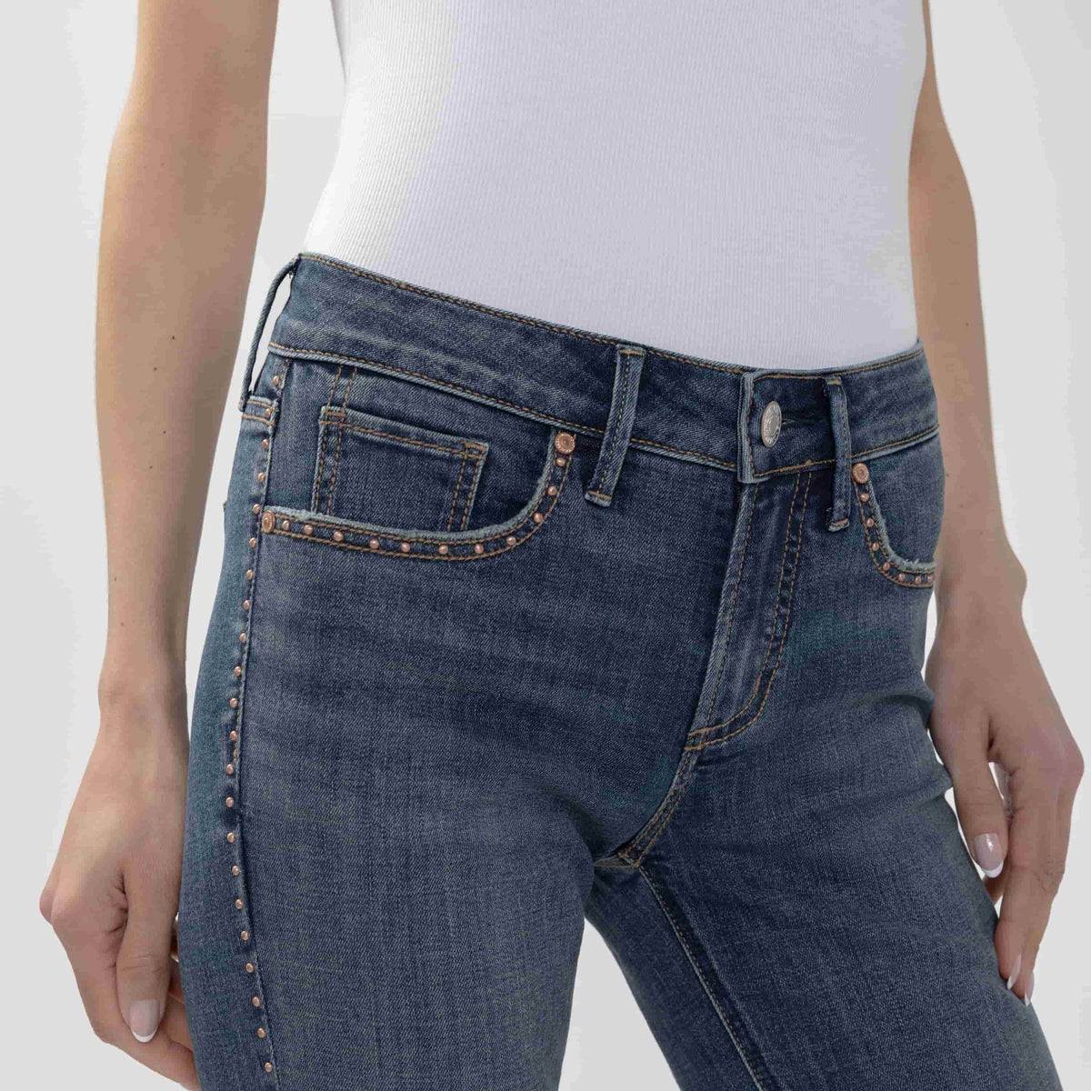 Model wearing Suki Slim Boot jeans in Seraphina with white ribbed top and belt.