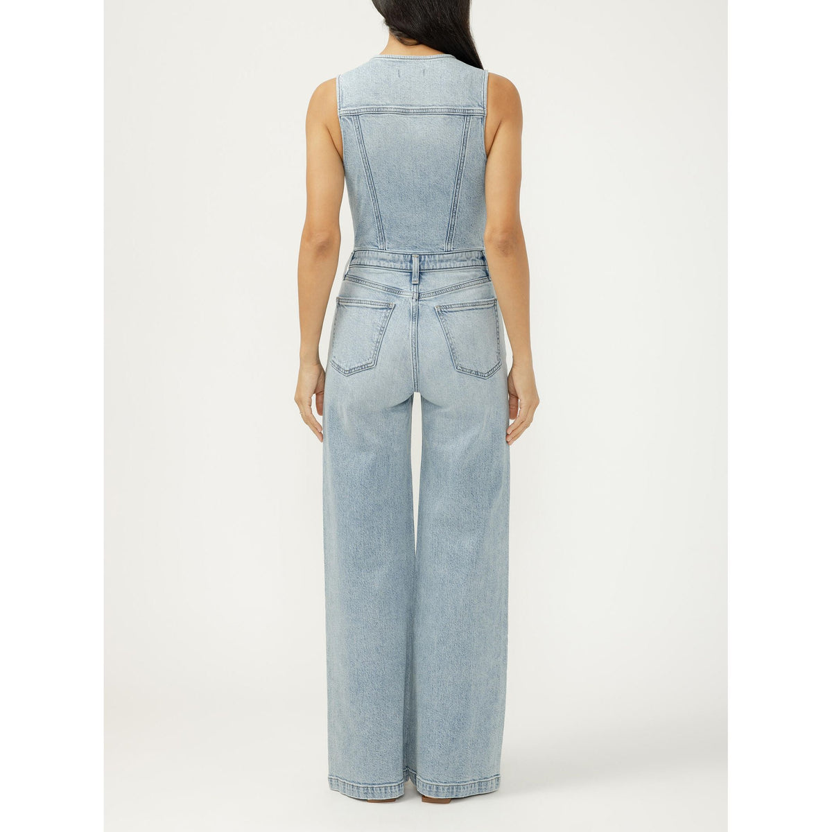 Back view of a silver wide-leg vest jumpsuit in Holbox, light denim with back pockets and seamed panels.