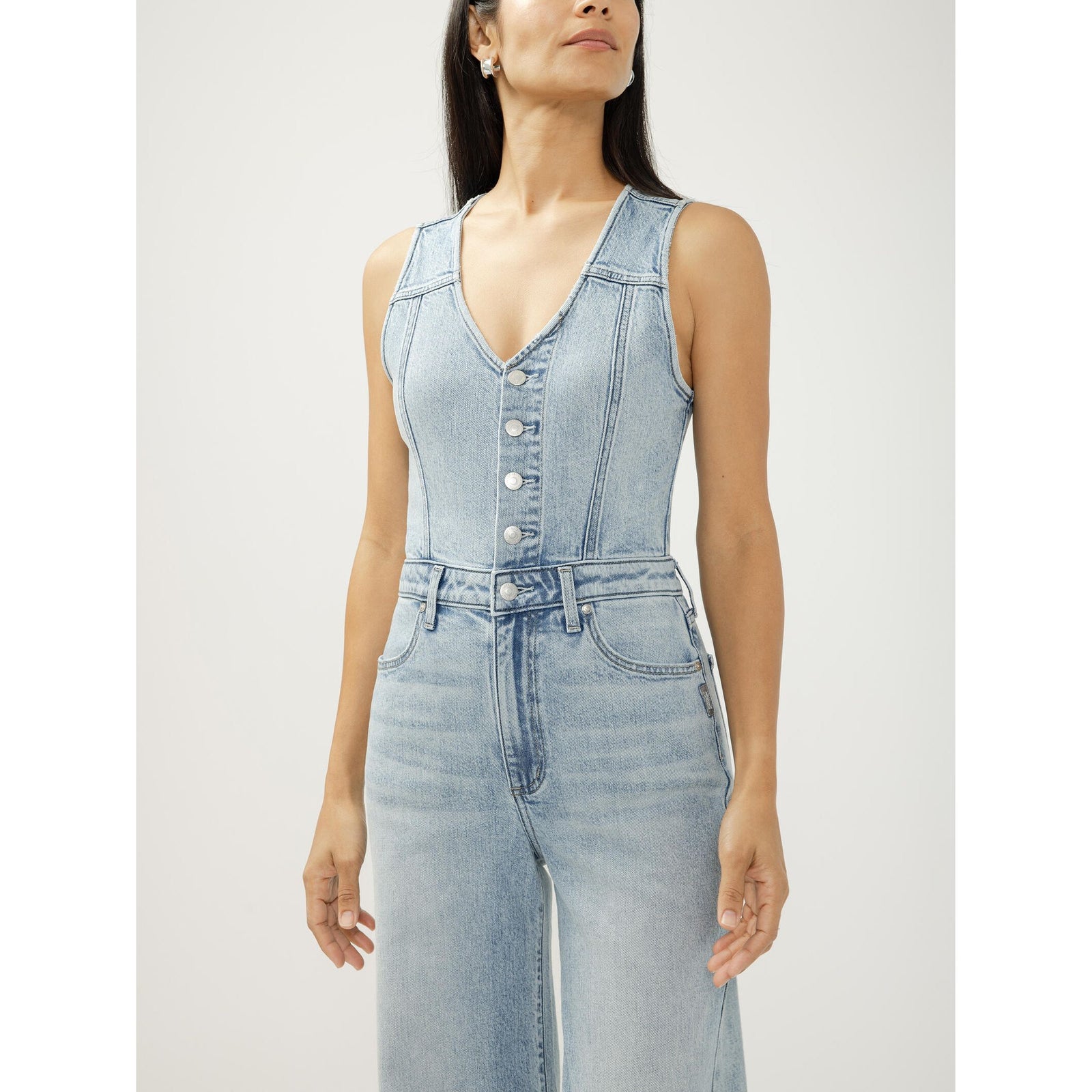 Light-wash denim vest jumpsuit with button-front closure and wide-leg silhouette on model.