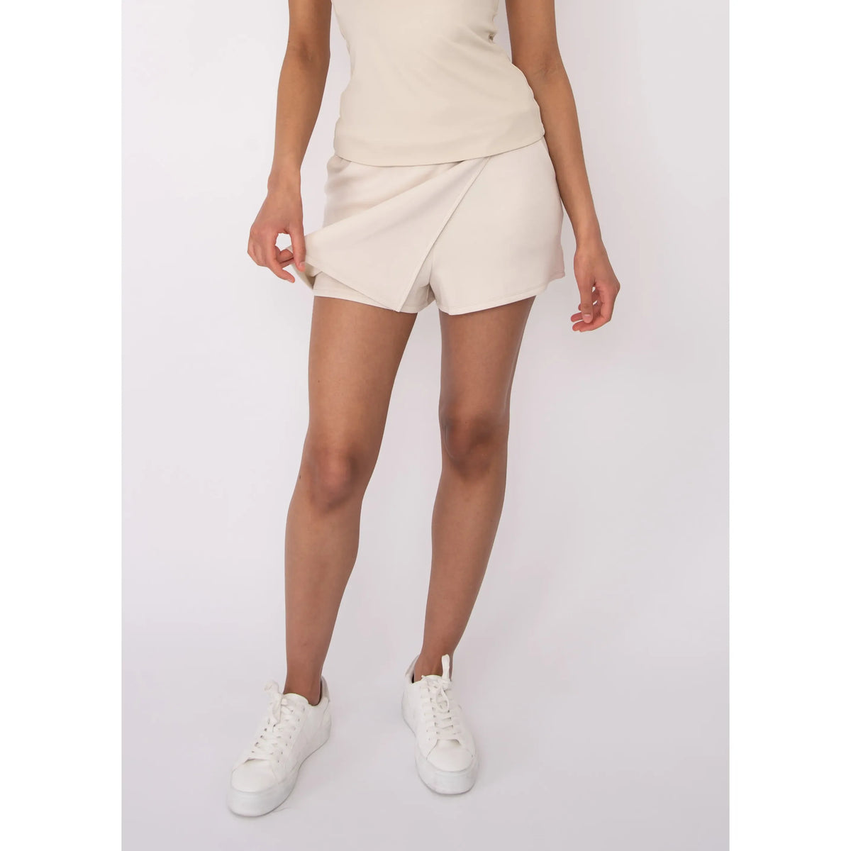 Starry Soft Knit Skort in beige with wrap-front overlay, paired with white sneakers for a casual summer look.