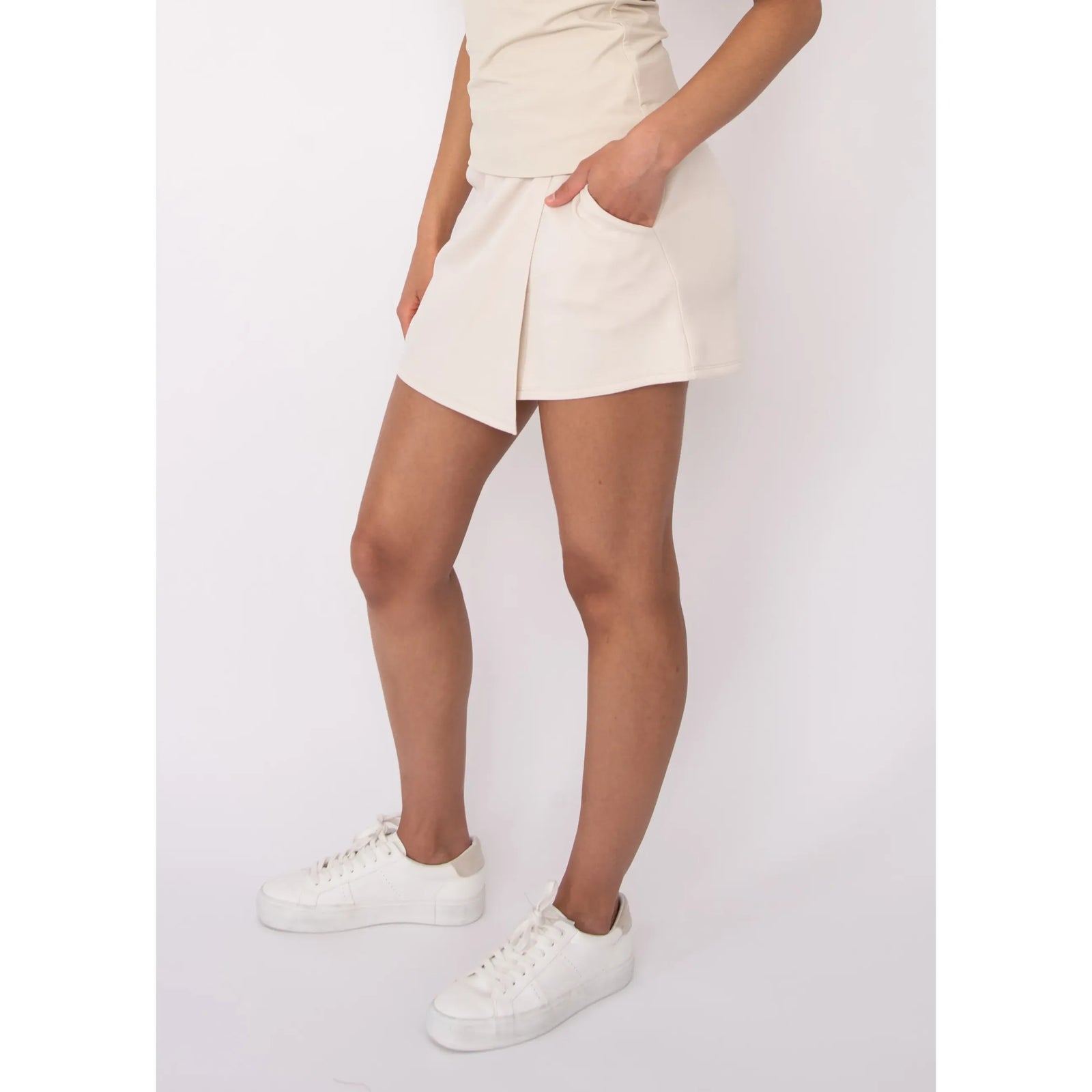 Beige Starry Soft Knit Skort on a model with a side pocket, paired with white sneakers.