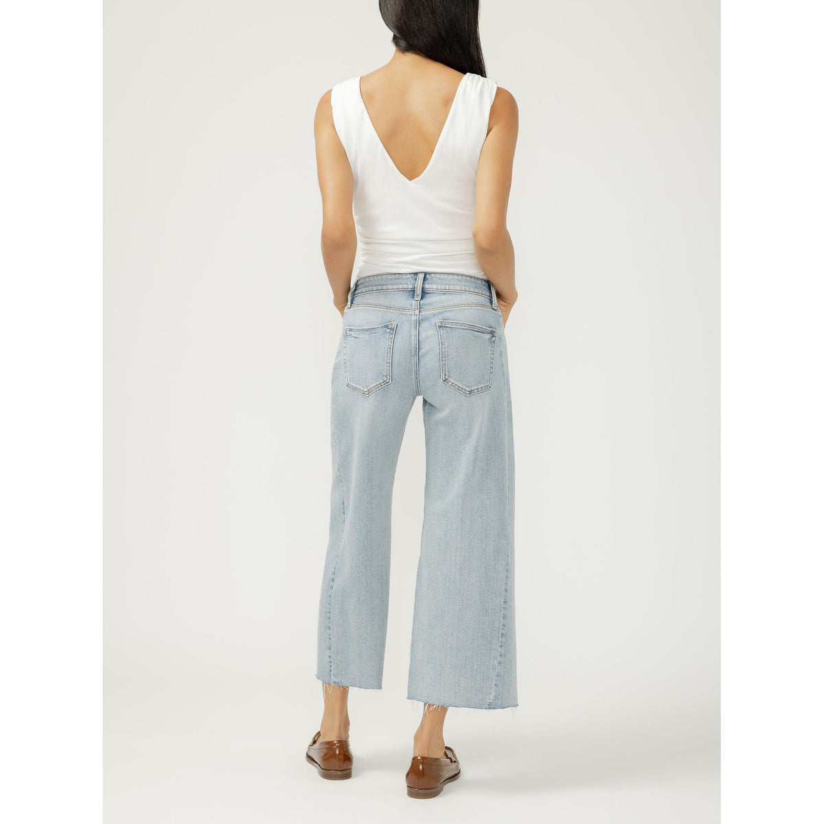 Back view of model wearing Silver Suki Wide Leg Cropped jeans in West End, light wash, mid-rise, frayed hem.