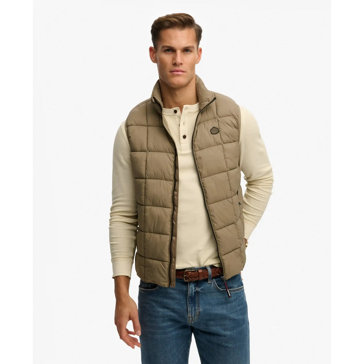 Superdry Box Quilt Fuji Lite Gilet in beige, quilted zip-front vest over a cream knit, paired with jeans.