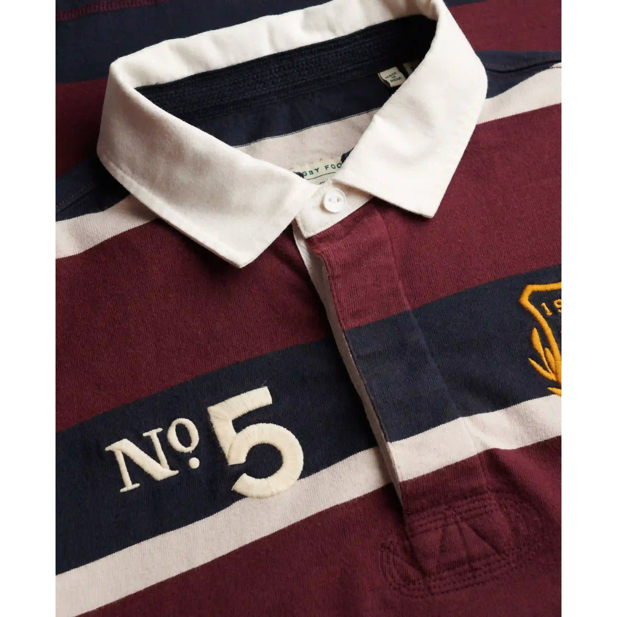 Superdry rugby shirt with maroon, navy, and white stripes, white collar, No. 5 embroidery and crest badge.