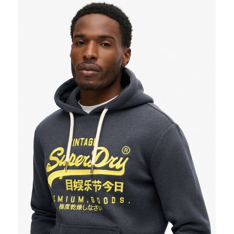 Man wearing navy Superdry Neon VL Graphic Hoodie with bright yellow neon logo and relaxed fit