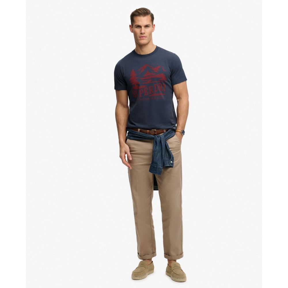 Male model in Superdrydry Retro Outdoor Relaxed Tee with vintage chest graphic, khaki pants and denim shirt tied.
