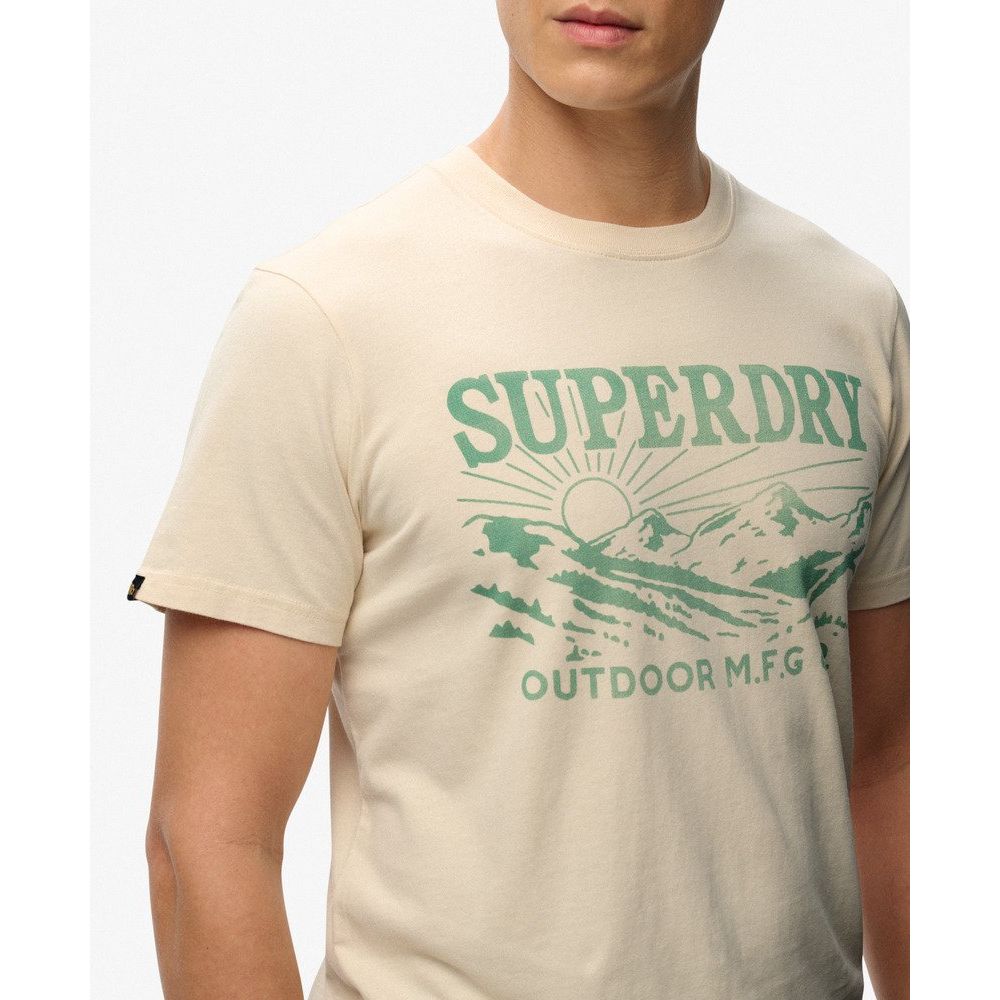 Man wearing beige Superdry Retro Outdoor Relaxed Tee with green vintage mountain graphic.