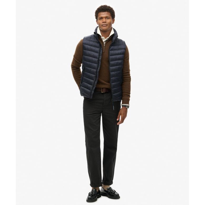 Man wearing navy Superdry Fuji Sport Padded Gilet over brown knit sweater, slim-fit padded vest with multiple pockets.