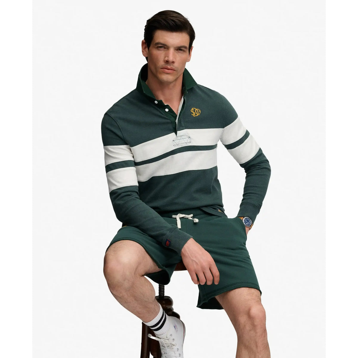 Male model in Superdry Vintage Athletic Stripe Rugby top, dark green with white stripes and embroidered chest logo.