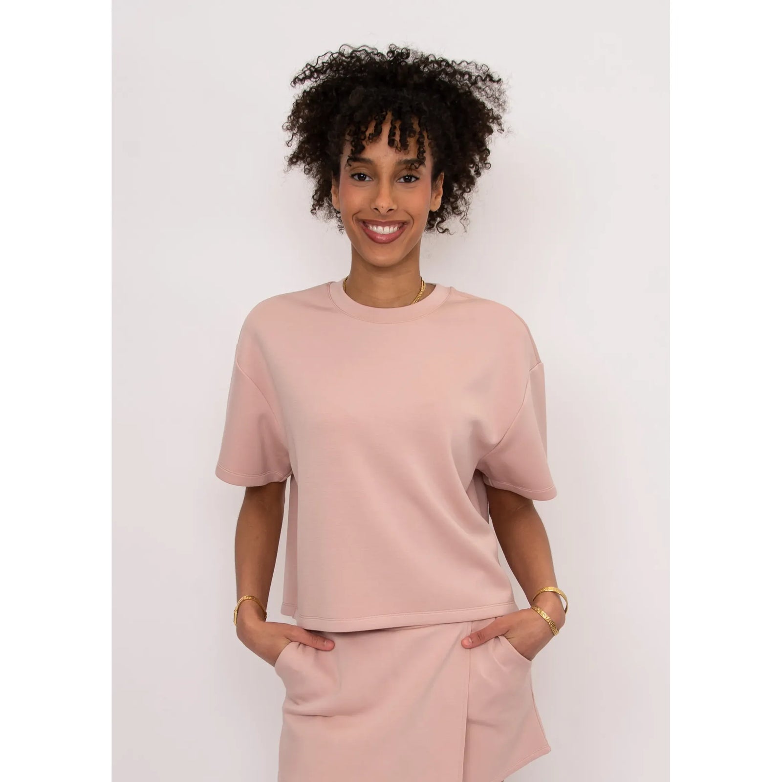 Dusty pink Tess Soft Knit Top with a boxy fit and short sleeves, styled with matching pants on a model.