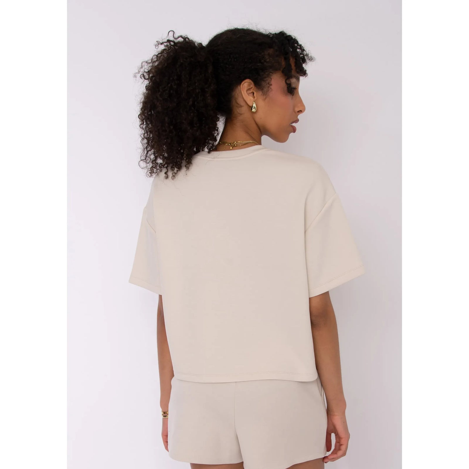 Beige Tess Soft Knit Top on model, back view, boxy relaxed fit with short sleeves
