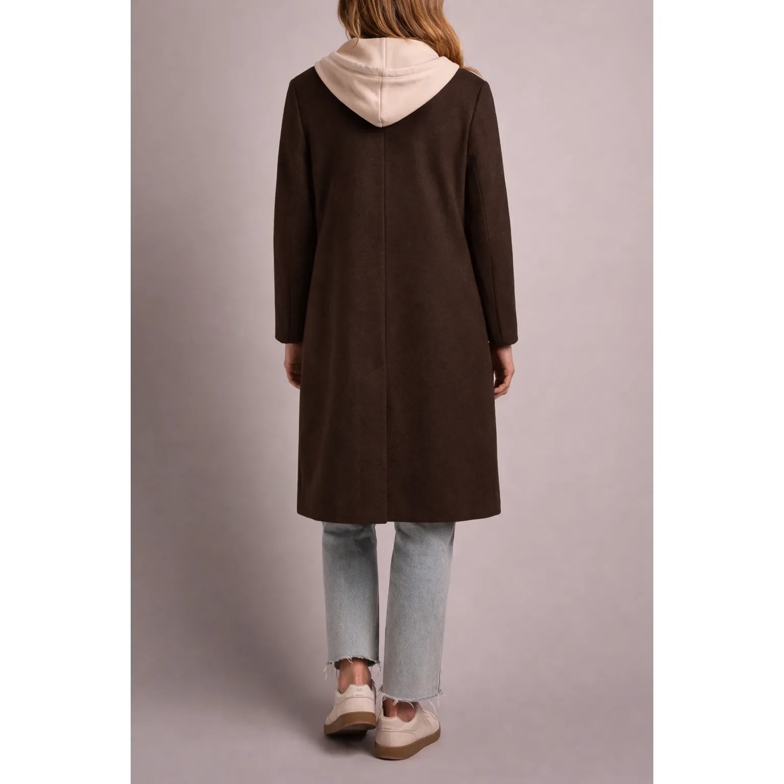 Back view of a brown tribal knit car coat featuring a cream fooler hoodie insert, paired with light wash jeans and cream sneakers.