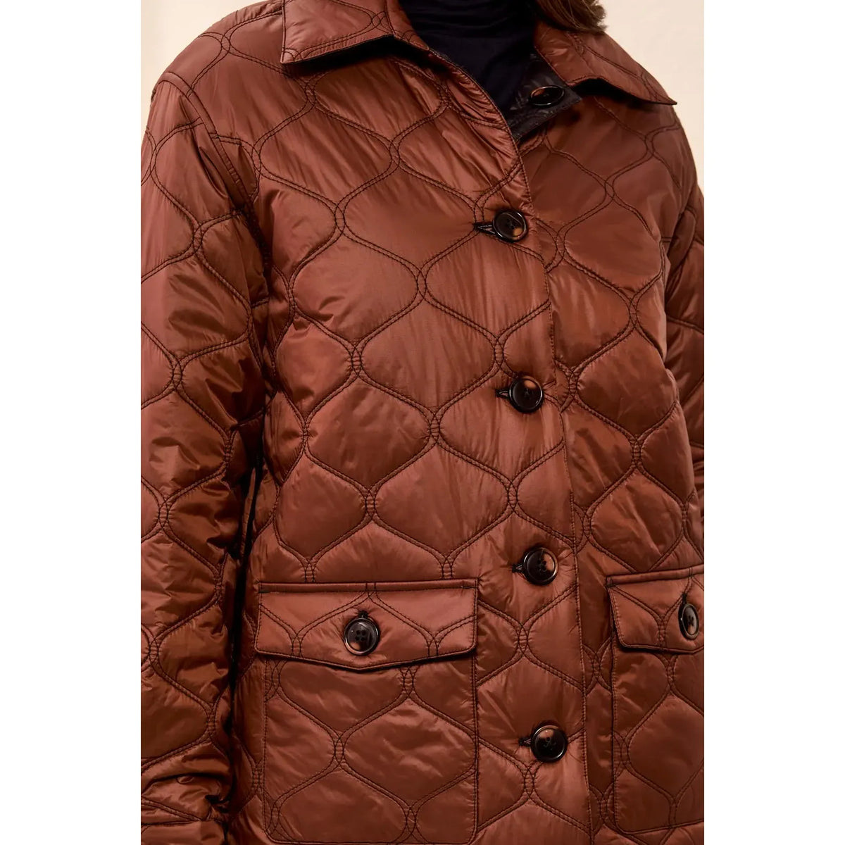 Copper-toned quilted jacket with geometric stitching, button closures, and flap pockets; reversible to black.