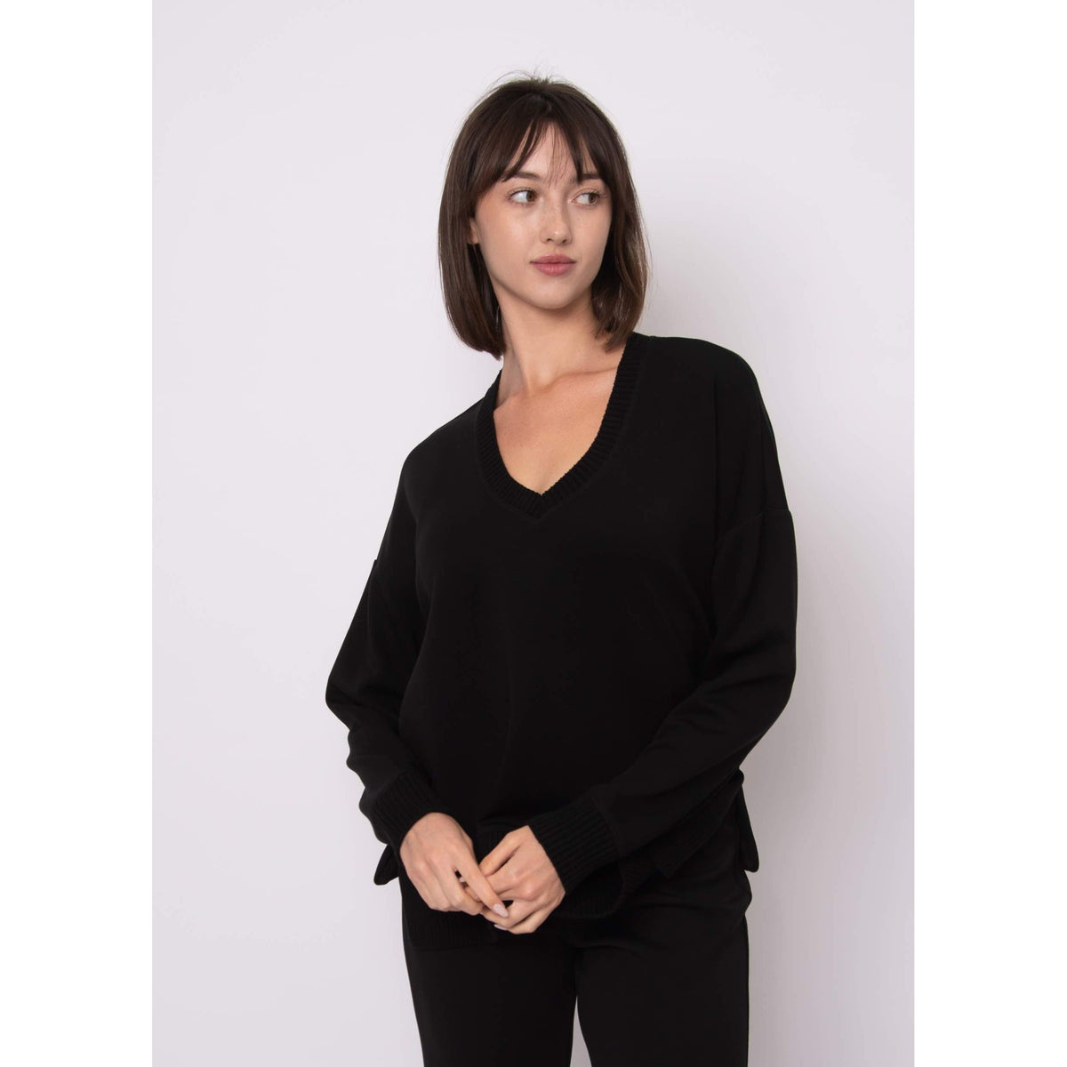 Model wearing Vixie Soft Knit Vneck Sweater in black with a ribbed Vneck, relaxed fit.