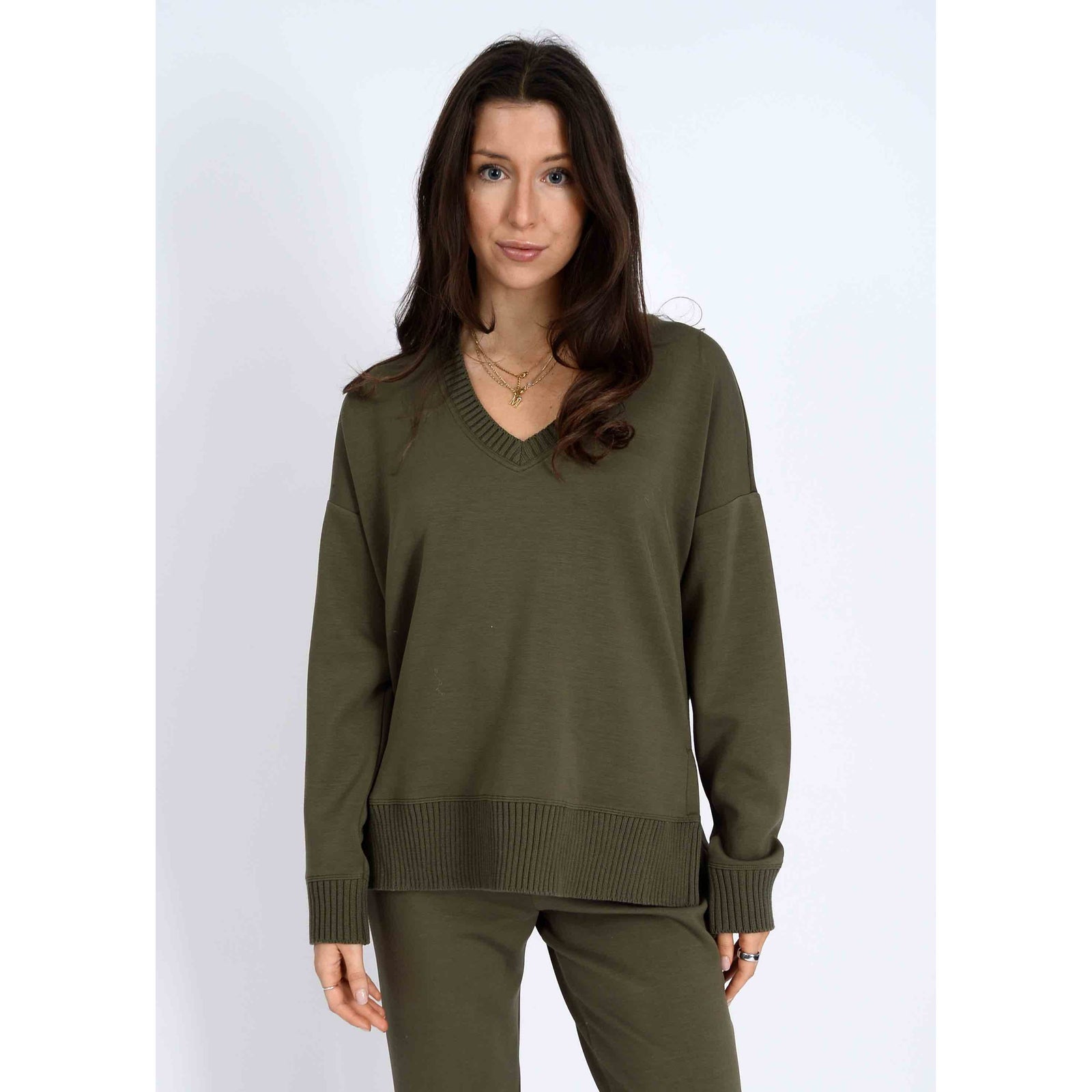 Model wearing olive-green Vixie Soft Knit V-Neck Sweater with ribbed hem and cuffs.
