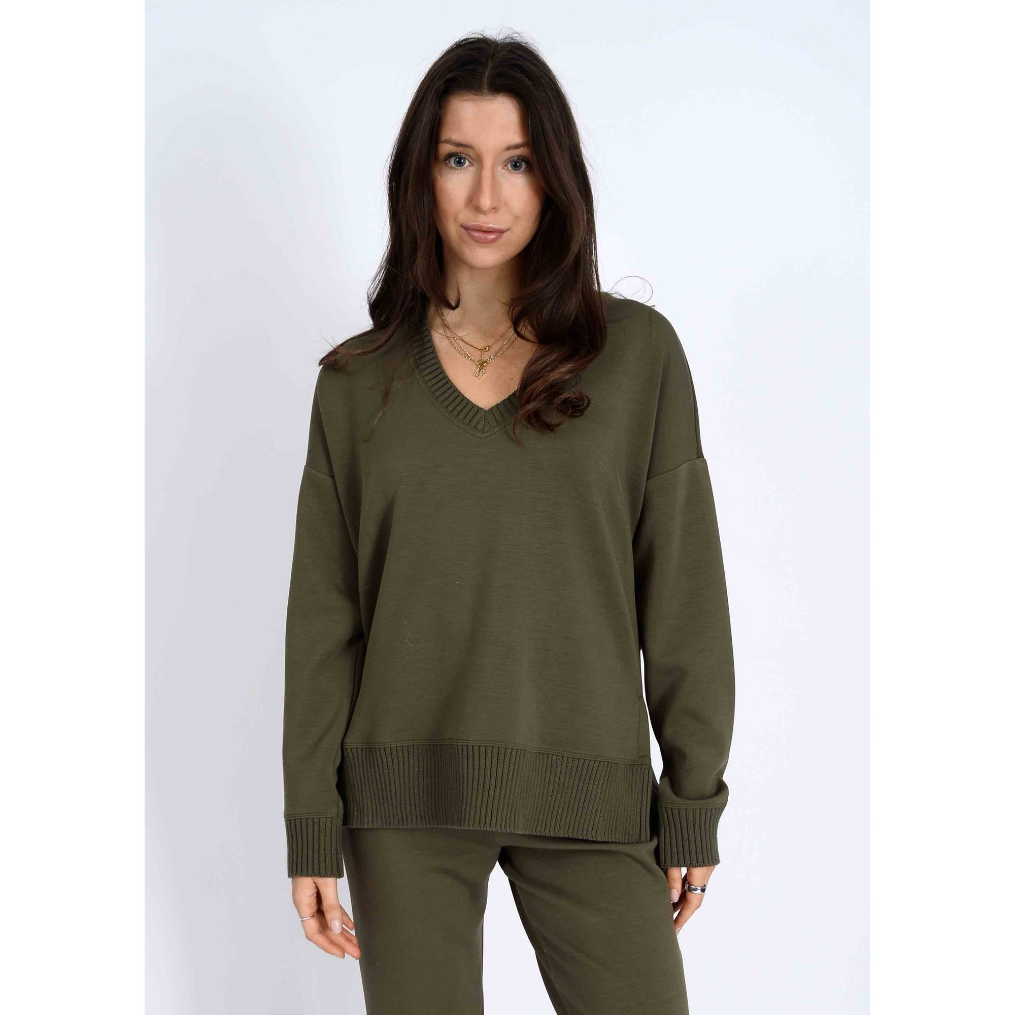Model wearing olive-green Vixie Soft Knit V-Neck Sweater with ribbed hem and cuffs.