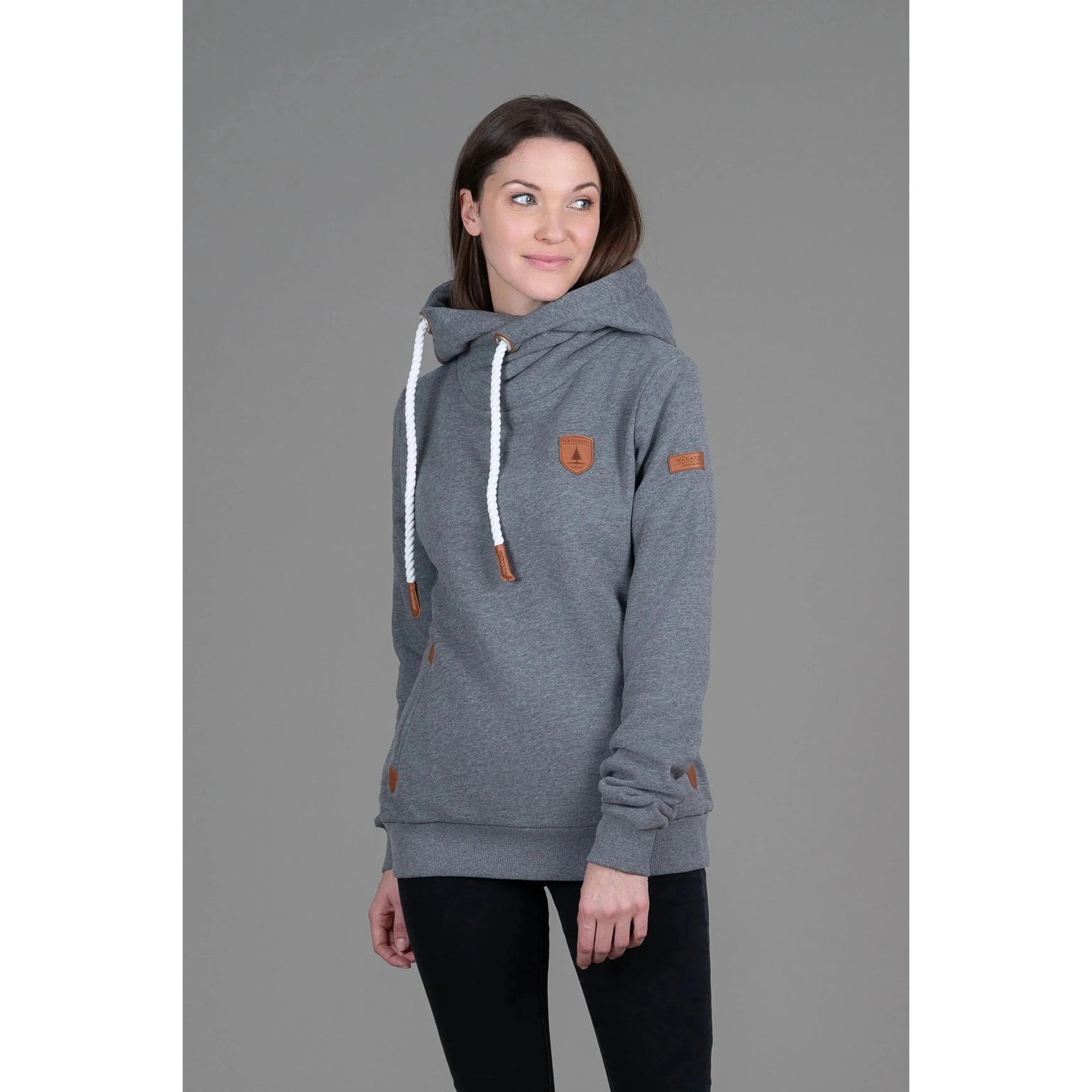 Wanakome Artemis Hoodie in heather grey on a model with attached hood, white drawstrings, and leather patches.