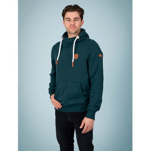 Wanakome Cascade Hoodie worn by Khaleel (size Large), teal cowl-neck with white drawstrings, vegan leather patches, front kangaroo pocket.