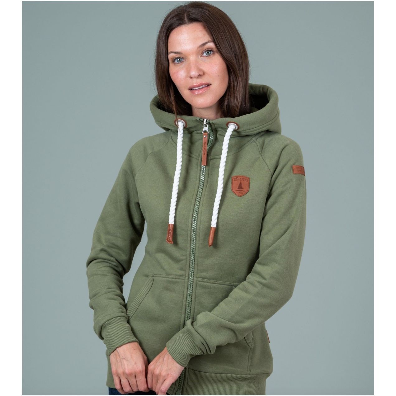 Olive Wanakome Hera zip-front hoodie with white drawstrings, leather patches on chest and sleeve, front pockets.