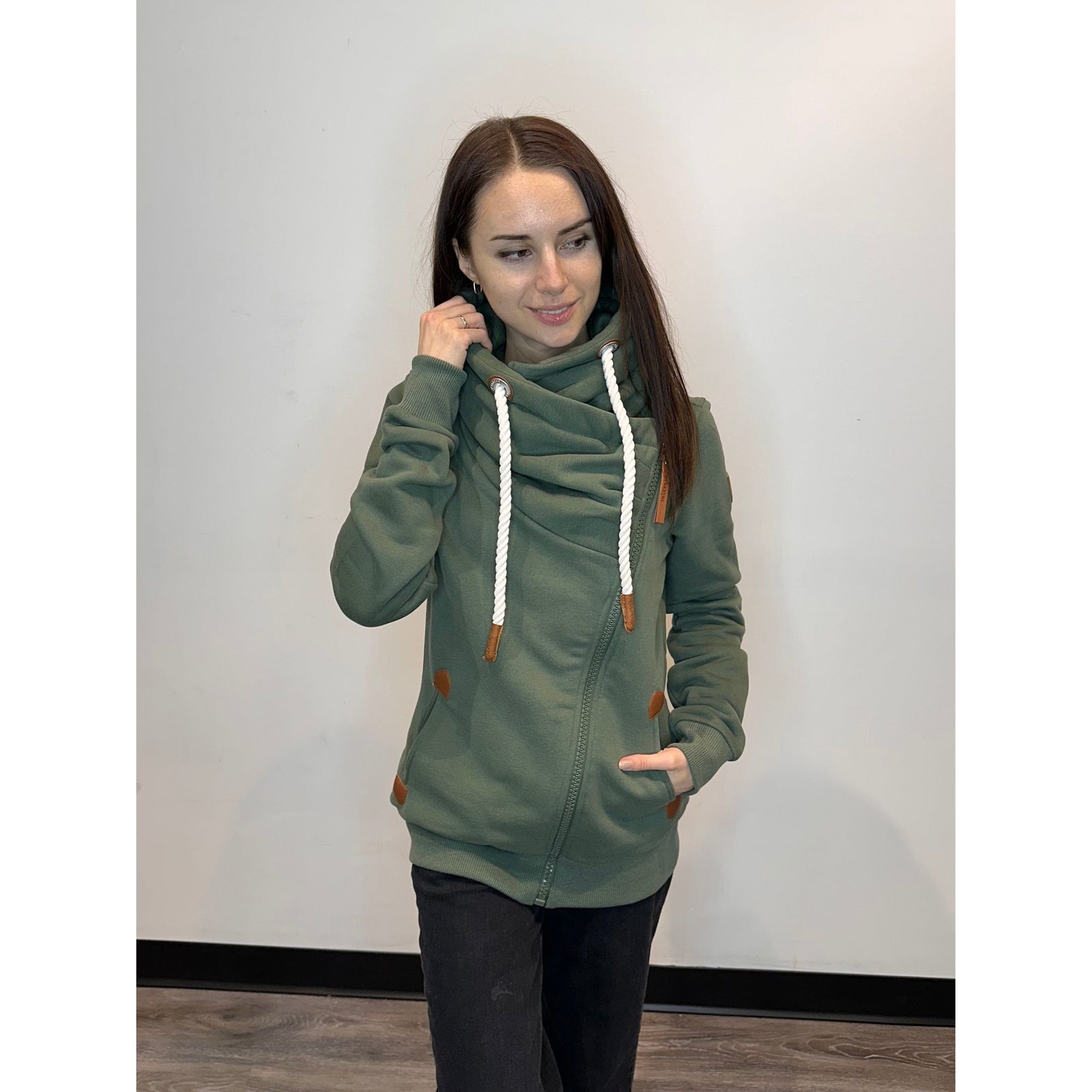 Wanakome Hestia Zip Up in moss green features a cozy funnel neck and stylish asymmetrical zipper design.
