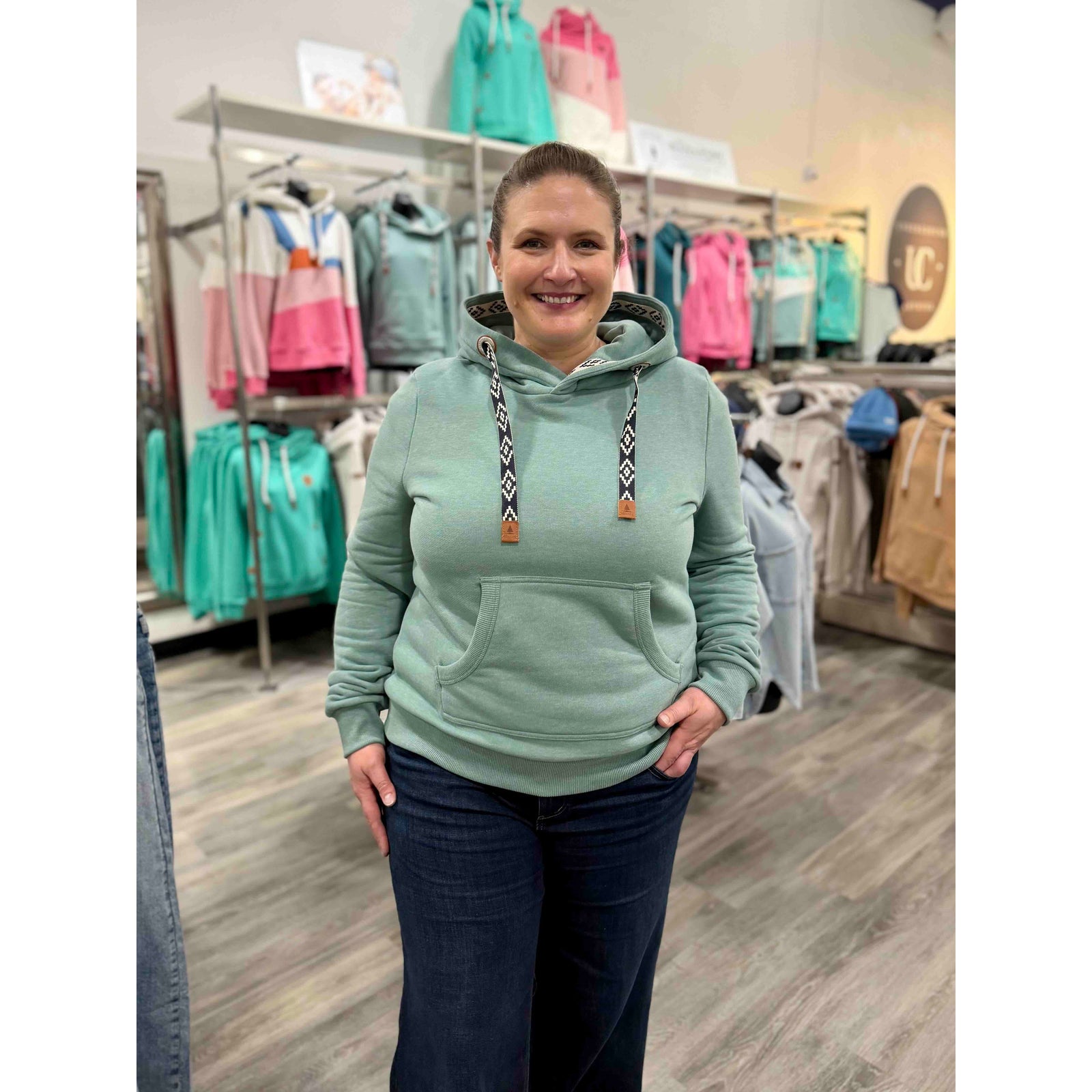 Wanakome Ikatt Hoodie: teal hoodie with cozy cowl neck, attached hood, patterned jacquard drawcords, front pocket.