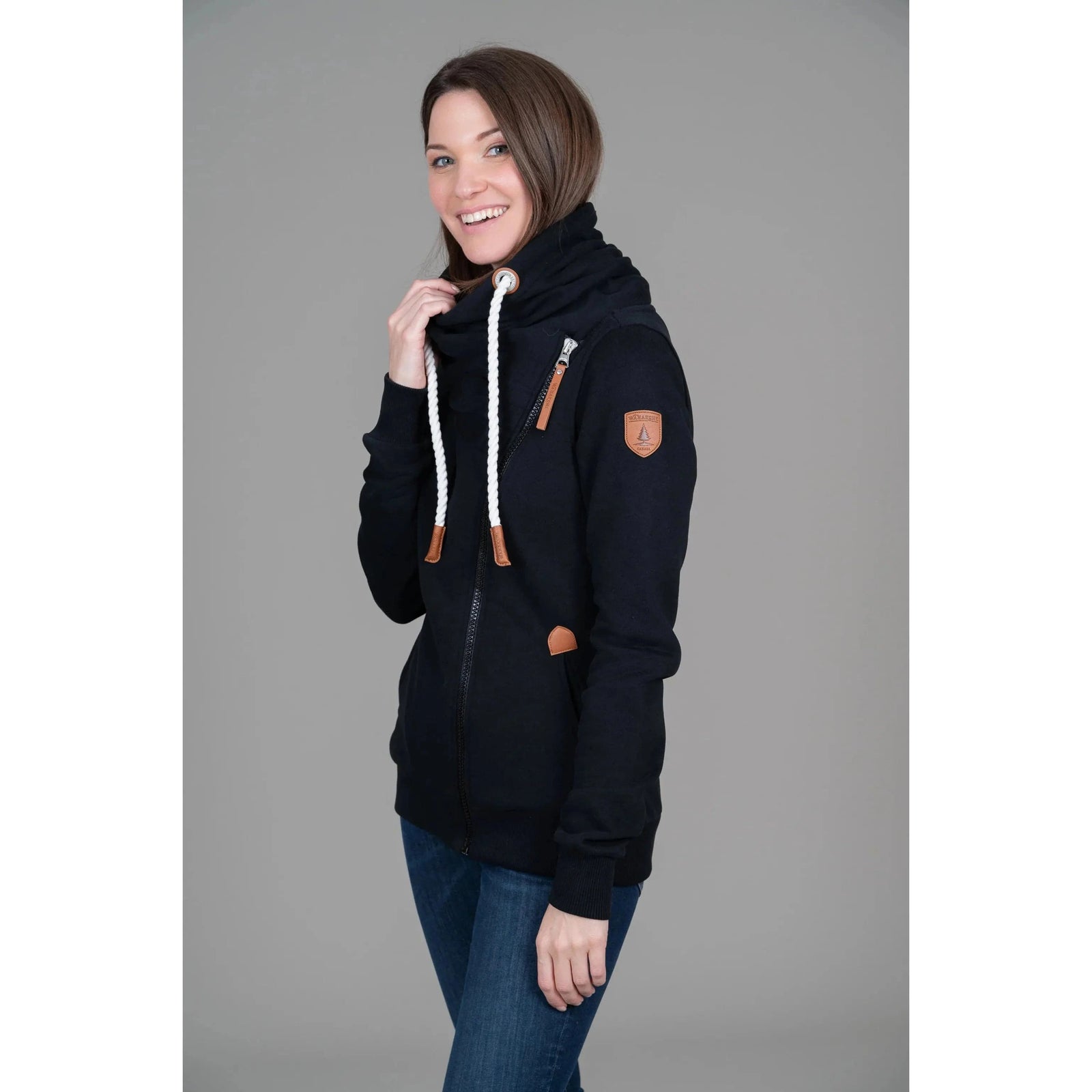 Stylish woman wearing the Wanakome Hestia Zip Up, featuring cozy funnel neck and asymmetrical zipper details.