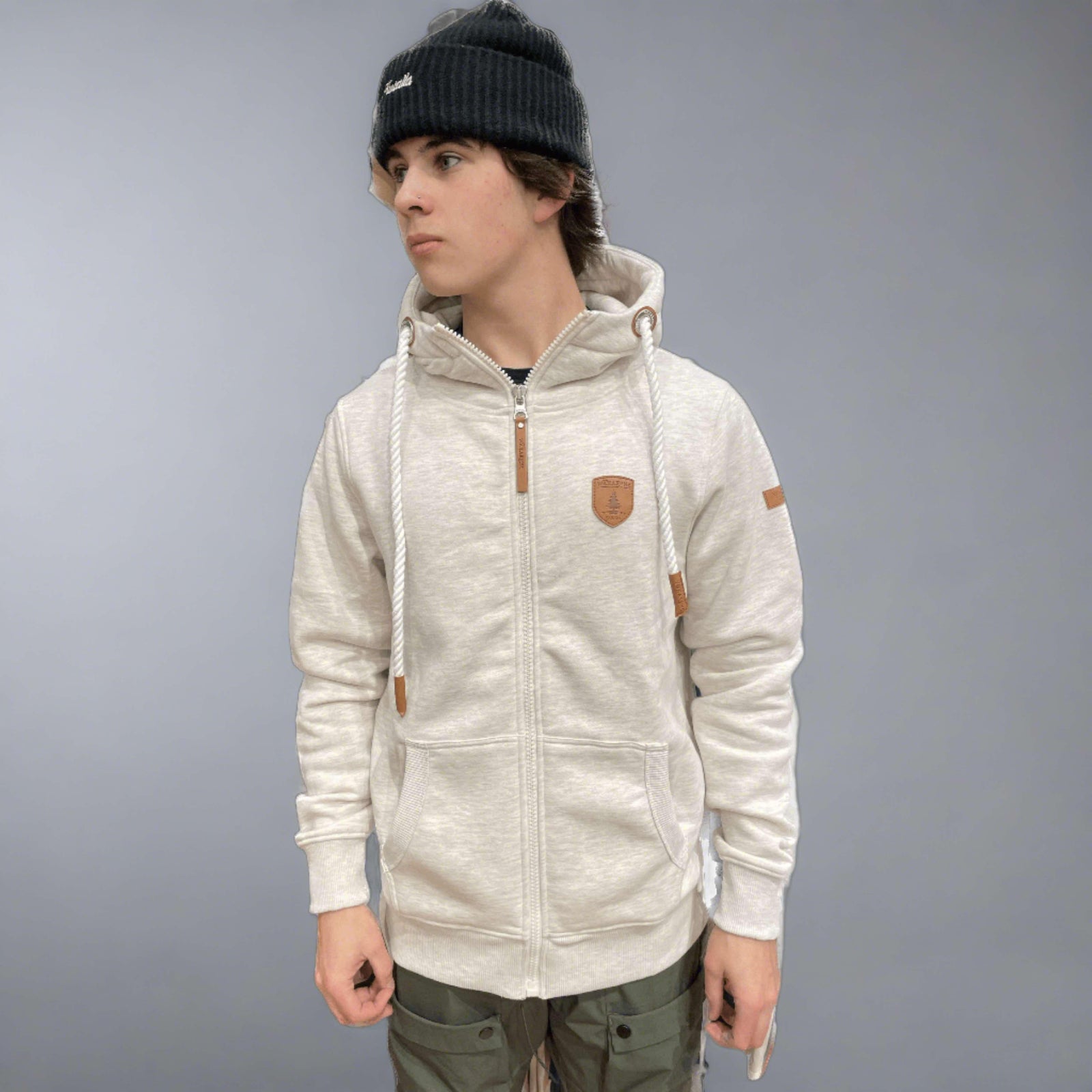 Wanakome Zeus Hoodie: heather oatmeal zip-up with rope drawstrings and leather accents on a model.