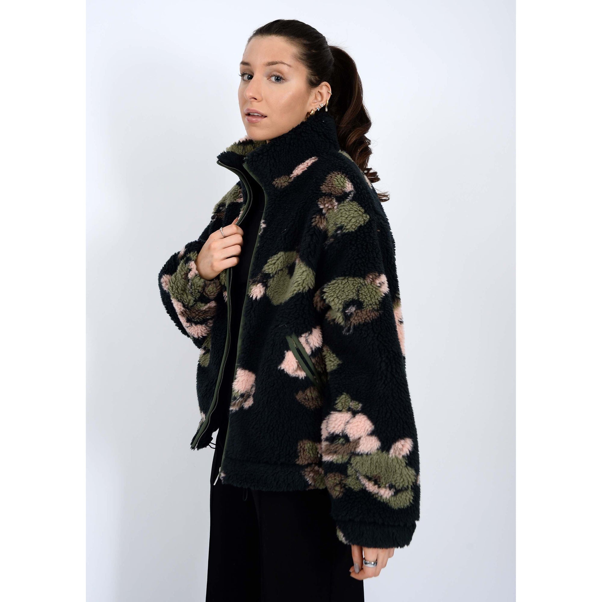 Whistler Sherpa Jacket worn by model, black teddy fabric with green-pink camo, collar, zip closure, drawstring hem