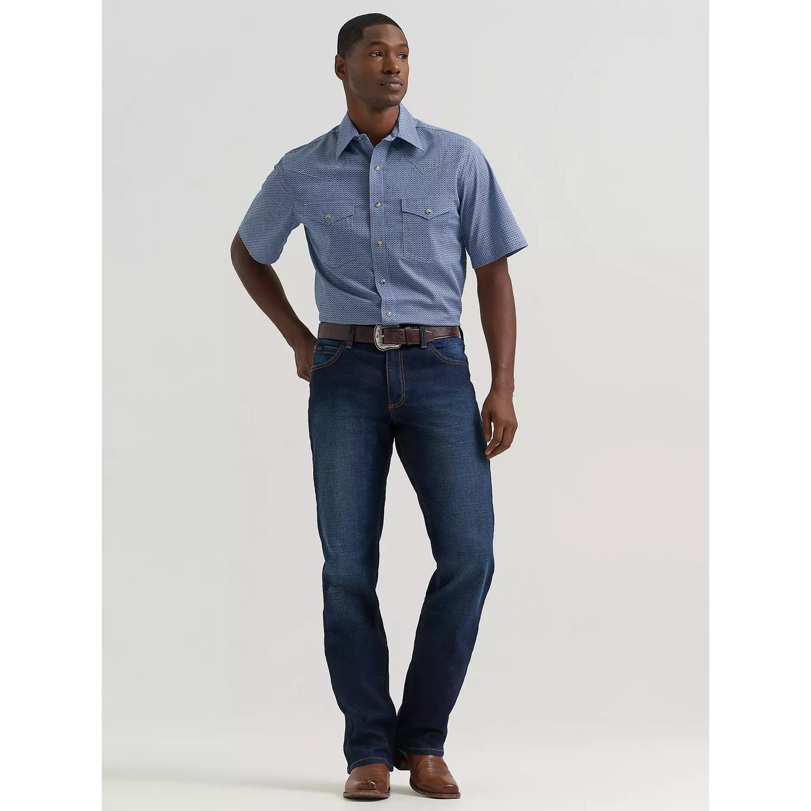 Man modeling Twilight Wrangler 20X Active Flex regular-fit stretch-denim jeans with a blue patterned short-sleeve shirt.