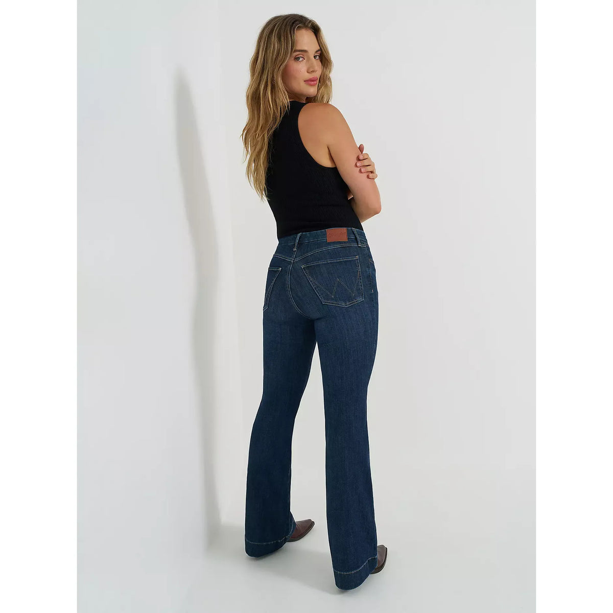Wrangler Bespoke Trouser in Alexandra: model wearing high-rise dark denim jeans with back pockets and leather patch.