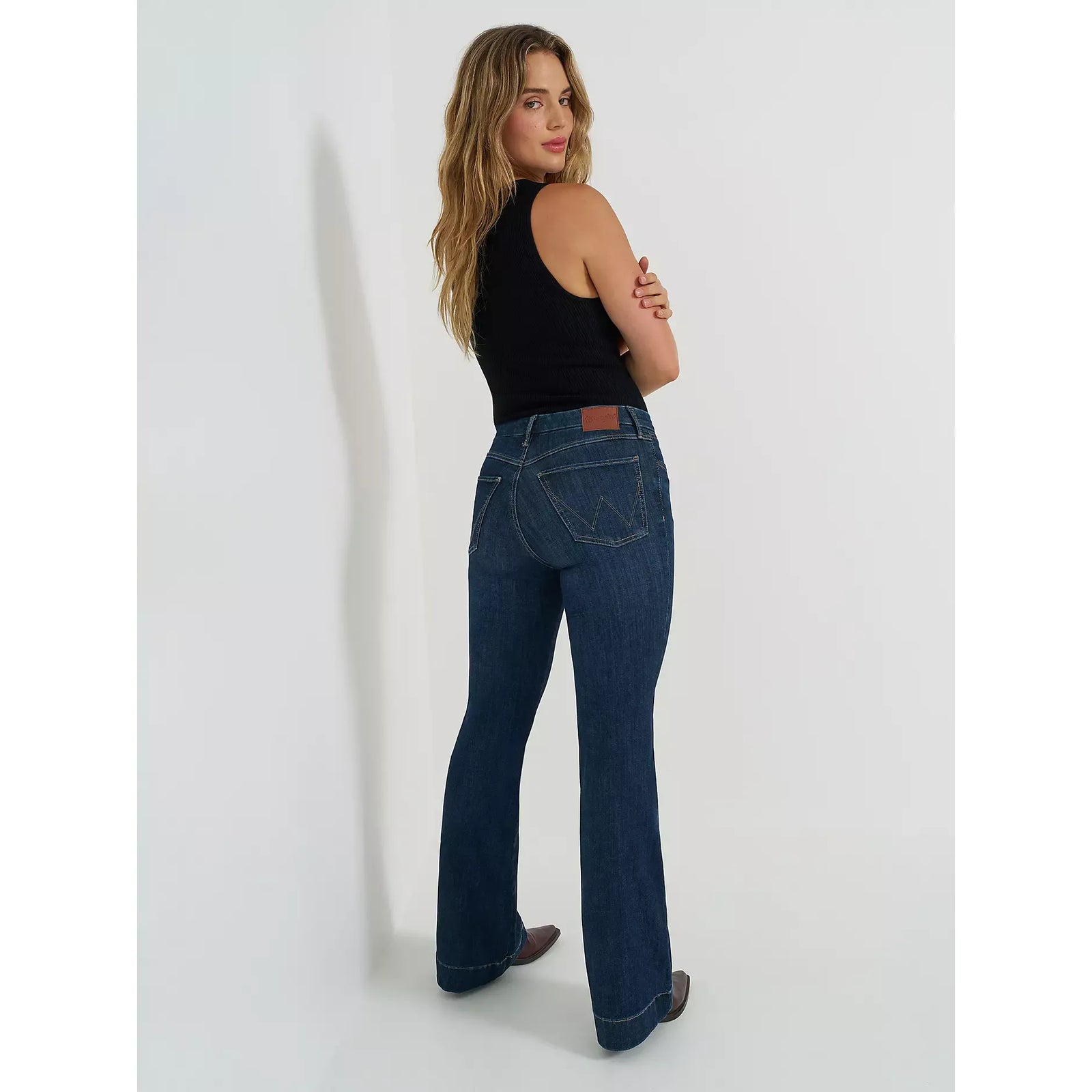 Wrangler Bespoke Trouser in Alexandra: model wearing high-rise dark denim jeans with back pockets and leather patch.
